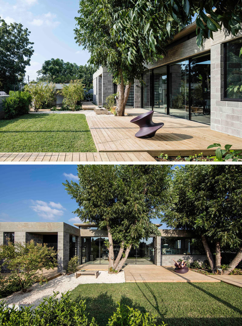 This modern house has a yard at the front of the house with a wood patio and a grassy lawn to give the children space to play.