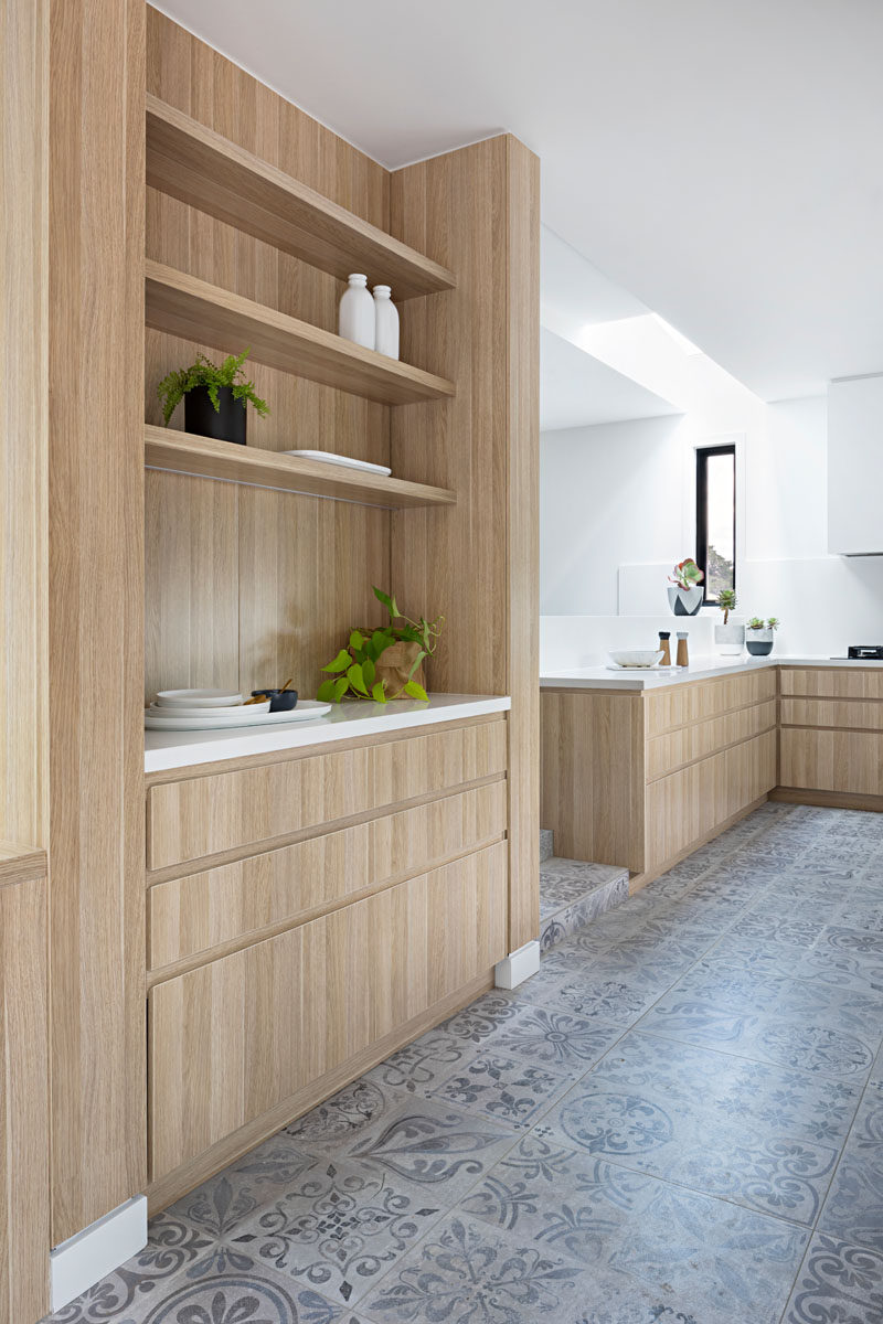 In this light wood kitchen, there's a separate space with built-in cabinetry and open shelves, ideal for extra plates and dishes or as a coffee station.