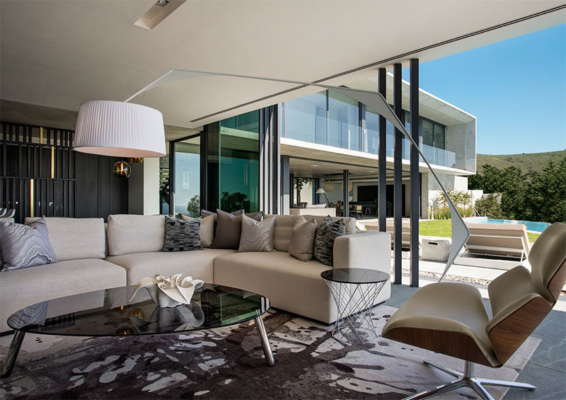 In this modern living room, sliding glass pocket doors open up to the backyard and swimming pool, and a comfortable L-shaped couch provides a place to watch a movie.