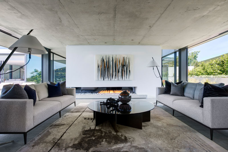 In this modern formal living room, large sliding glass doors can be opened to enjoy the breeze, and on a cooler night, a fireplace positioned within a white partition wall adds warmth.