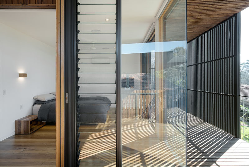 The master bedroom in this modern house is surrounded by windows that allow it take advantage of the landscape outside but also features a black privacy screen that prevents unwanted attention while in the bedroom.