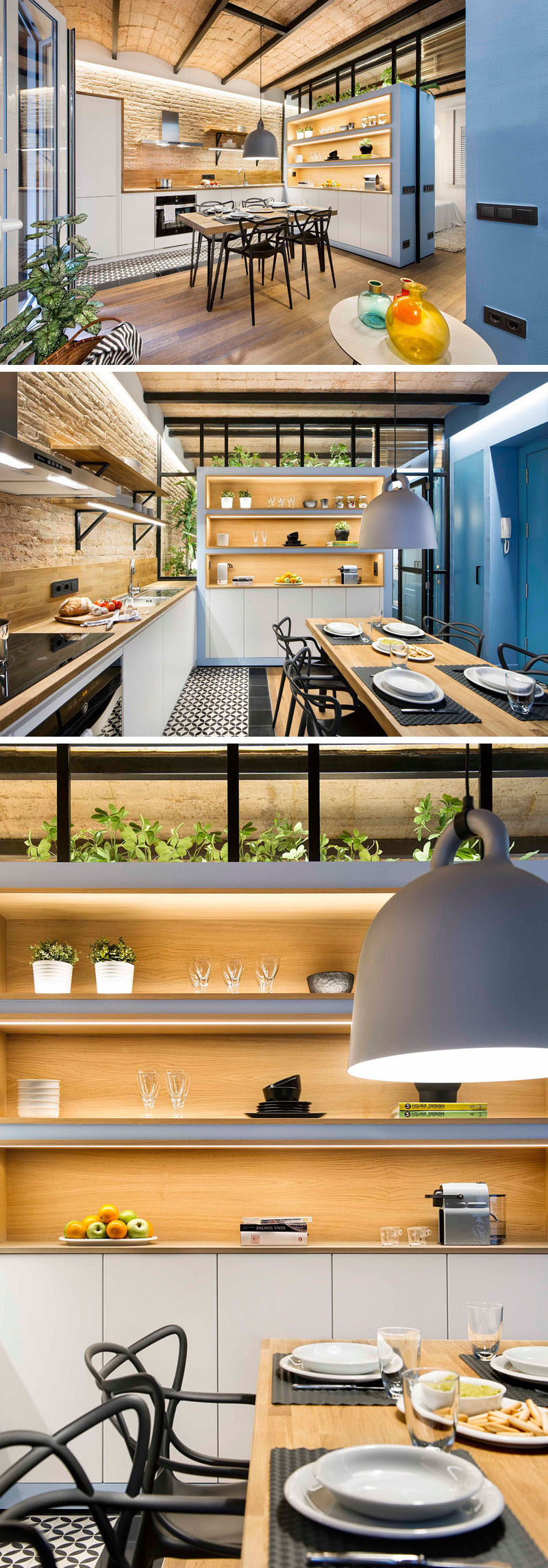 In this small apartment, a wooden table in the kitchen with steel black legs and black chairs acts as a dining table and a when needed a provides extra counter space. Behind the dining table, a large storage unit with open shelves, built-in lighting, and white cabinets on the bottom provides extra storage and light, and also doubles as a privacy wall between the living/kitchen area and the bedroom.