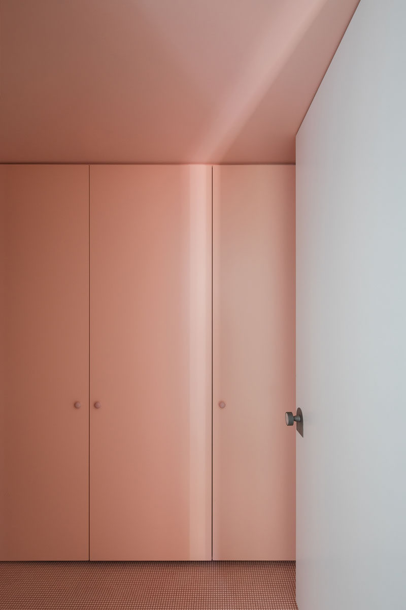 In this simple laundry room, small square peach tiles on the floor match the color of the cabinets that conceal the washer and dryer.