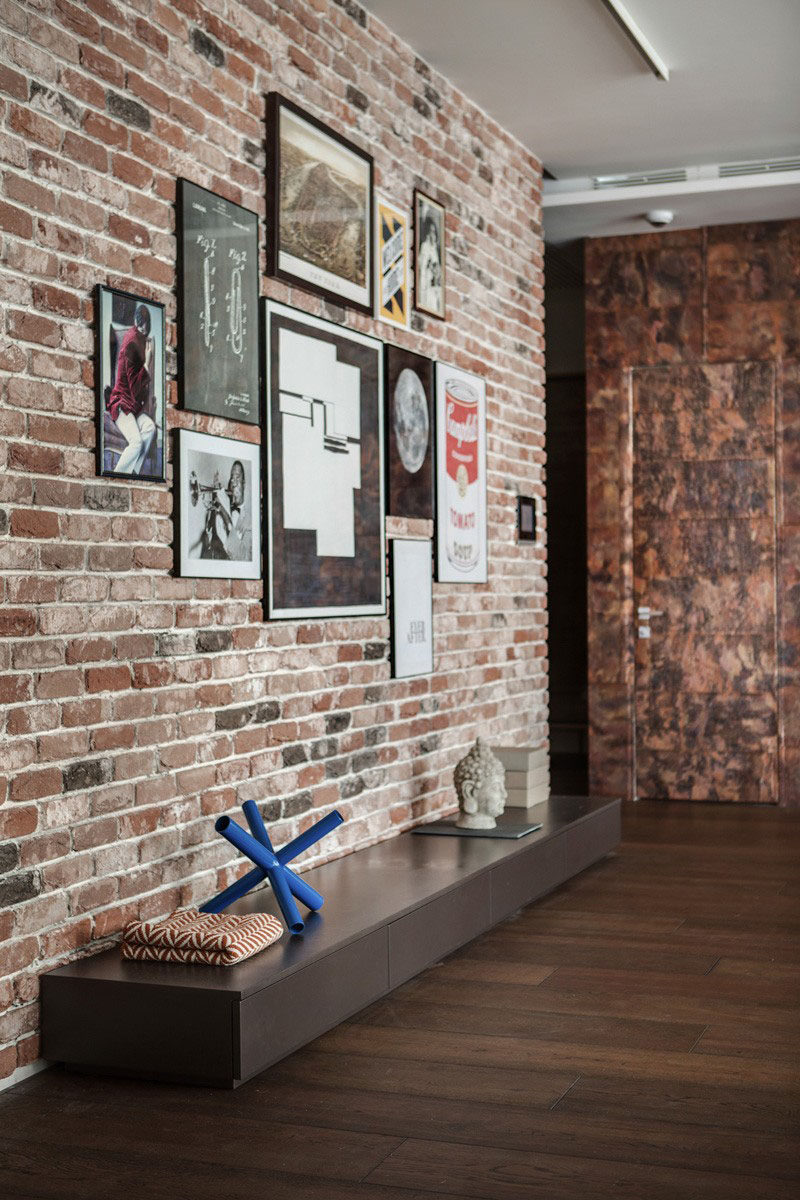 Artwork of various sizes have been hung on this exposed brick wall to add more life to the space, and the thin picture frames allow the pieces to stand out.