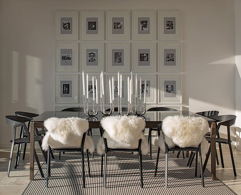 The gallery wall behind this dining table was thoughtfully created by framing black and white photos in all the same frames to create an organized and personal wall of art.