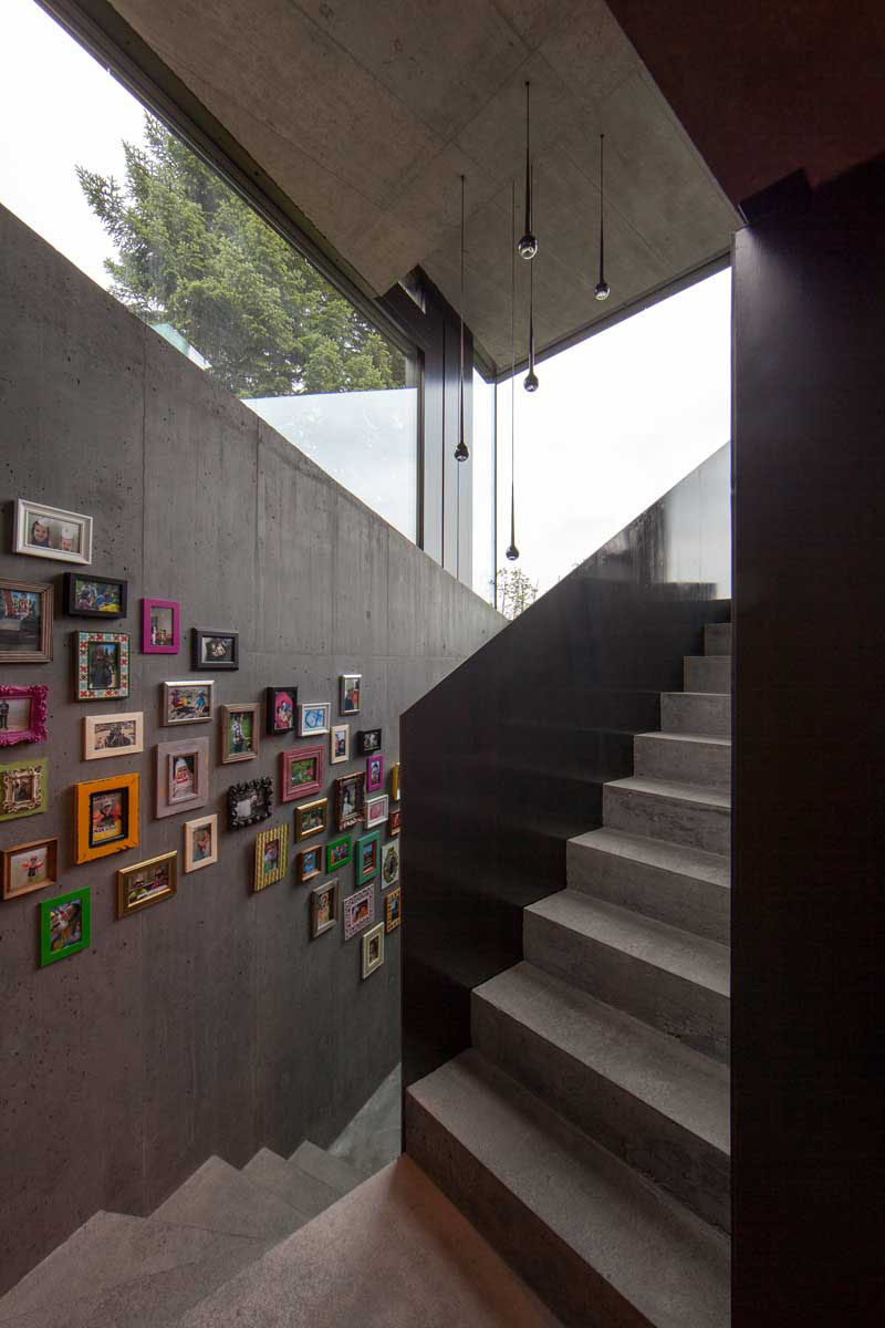 The colorful photo gallery on this wall leading down the stairs pop out against the grey concrete behind them and help to brighten up the staircase.