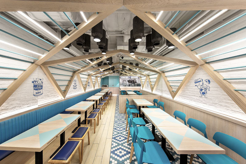 Atelier E have completed this modern restaurant design filled with blues and wood, was inspired by elements found in a traditional dairy farm, like a pitched roof and milk cans.