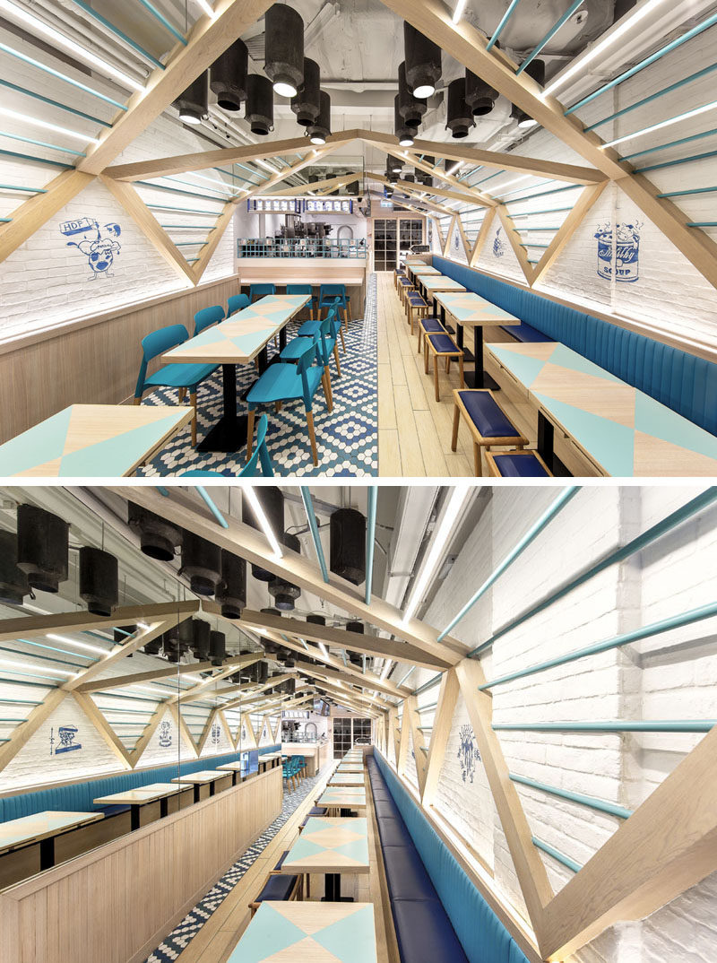 Blue banquette seating runs the length of one side of this modern restaurant, while tables and chairs have been arranged on the opposite wall, creating a cleanly organized and geometrical interior arrangement.