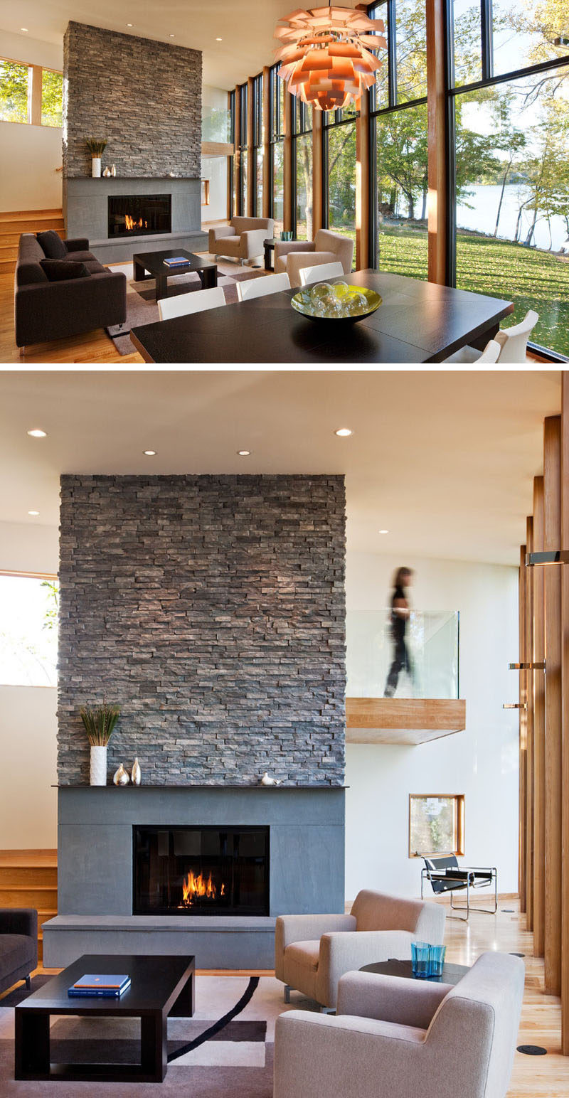 In this modern living room, a large gas fireplace covered in stone hides the staircase from view.