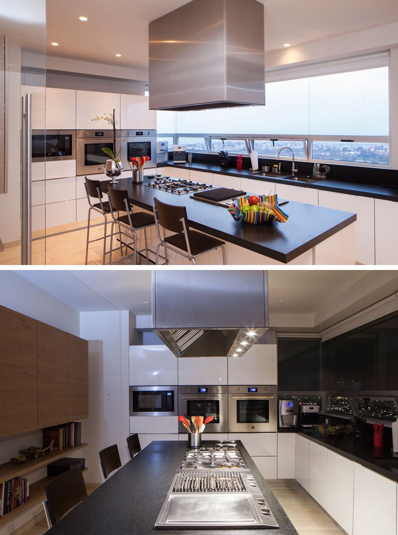 In this modern kitchen, a large window floods the space with natural light, while the white cabinets have been paired with black countertops and stainless steel appliances. To contrast the white cabinets, there's also a section of wood cabinetry on one wall.