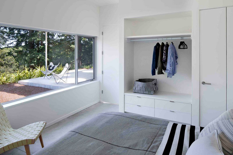 This modern guest bedroom has a large window to provides view and natural light to the room, and a built-in open closet is a great space for guests to hang their clothes.