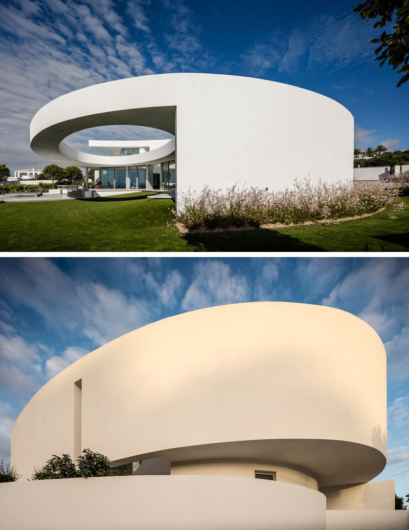 This modern house features a curved wall that wraps around from the front to the rear and opens to reveal a large elliptical cut-out.