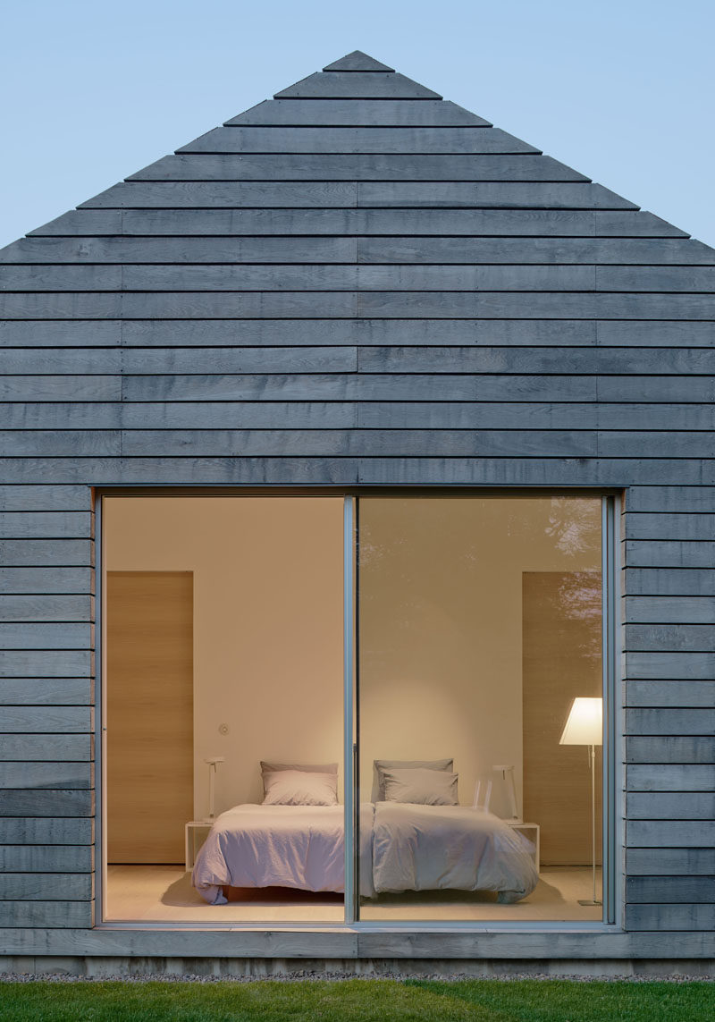 Horizontal wood plank siding covers this modern house, while sliding glass doors open the bedroom up to the outdoors.