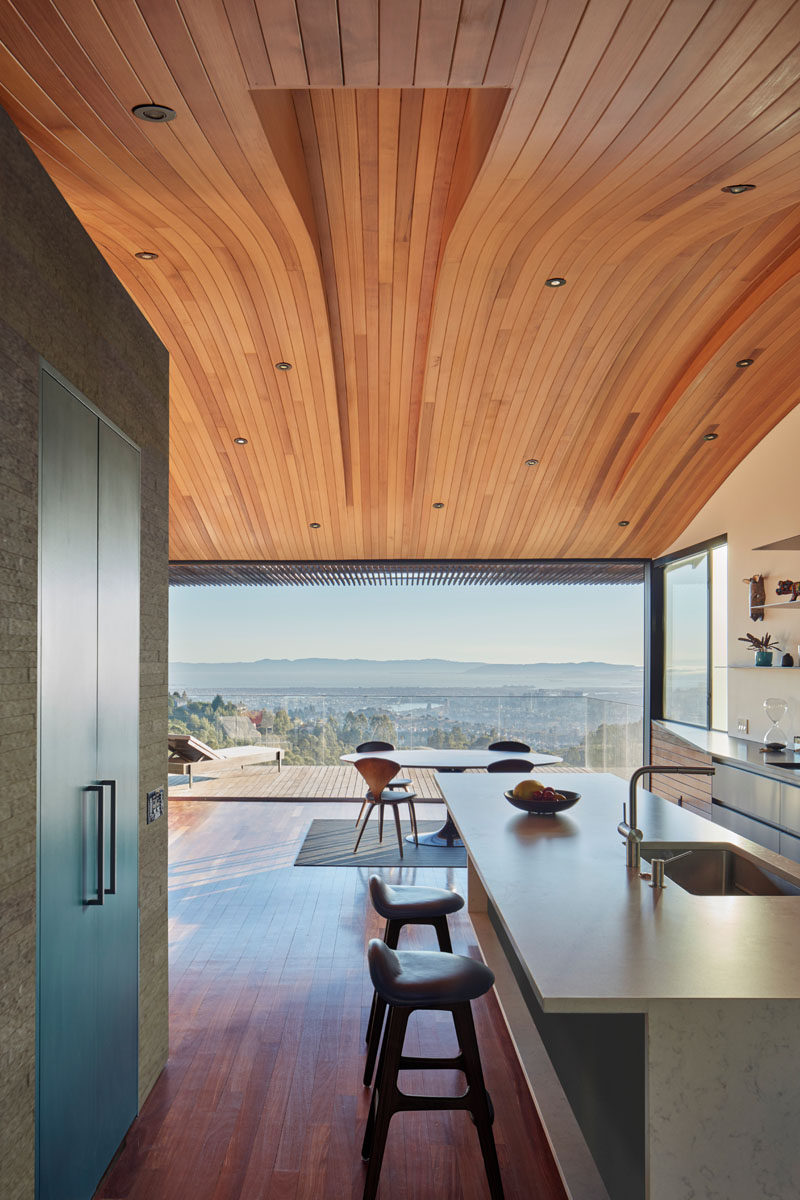 This modern home has a curved wood ceiling with the long sections of wood helping to elongate the interior and draw your eye to the balcony and view.