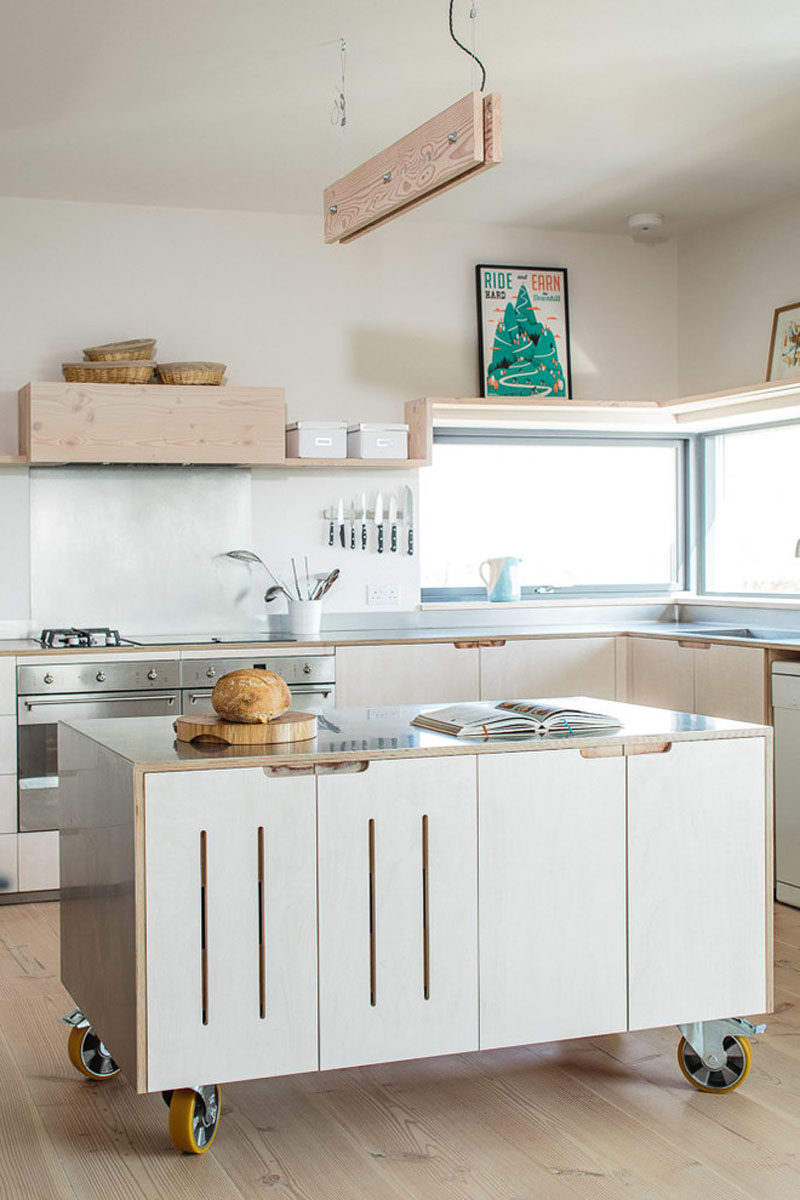 A stainless steel surface and large industrial wheels on the bottom of this simple movable kitchen island give it an industrial look while still keeping the overall look of the kitchen minimalist and bright.