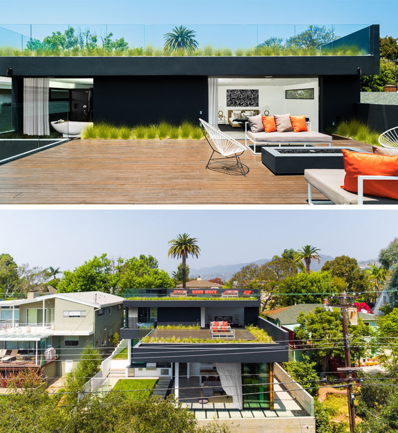 The wood rooftop deck located off the master bedroom in this modern house, has a lounge area surrounding a standalone fireplace, while plants that soften the hard edge where the deck meets the wall.