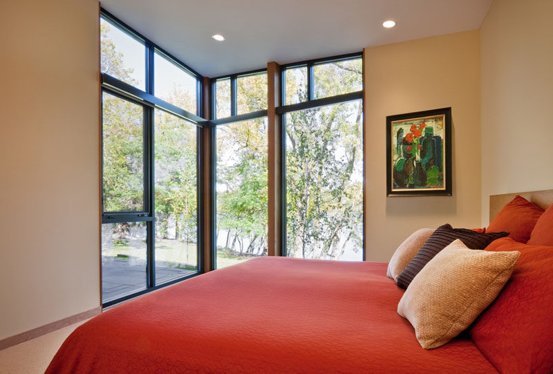 Large floor to ceiling windows in this modern bedroom let in lots of natural light and take advantage of the lakeside views at all hours of the day.