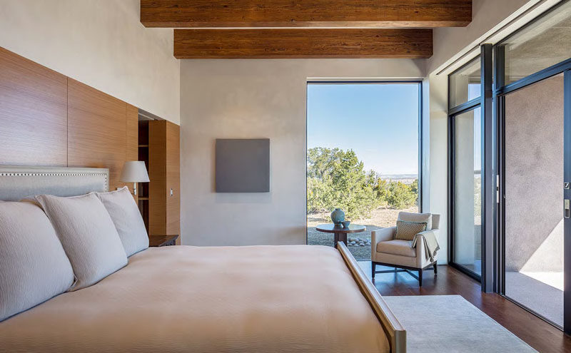 In this simple master bedroom, large windows provide picturesque views of the surrounding landscape, and sliding glass doors allow the home owner to enjoy the porch directly from their bedroom.