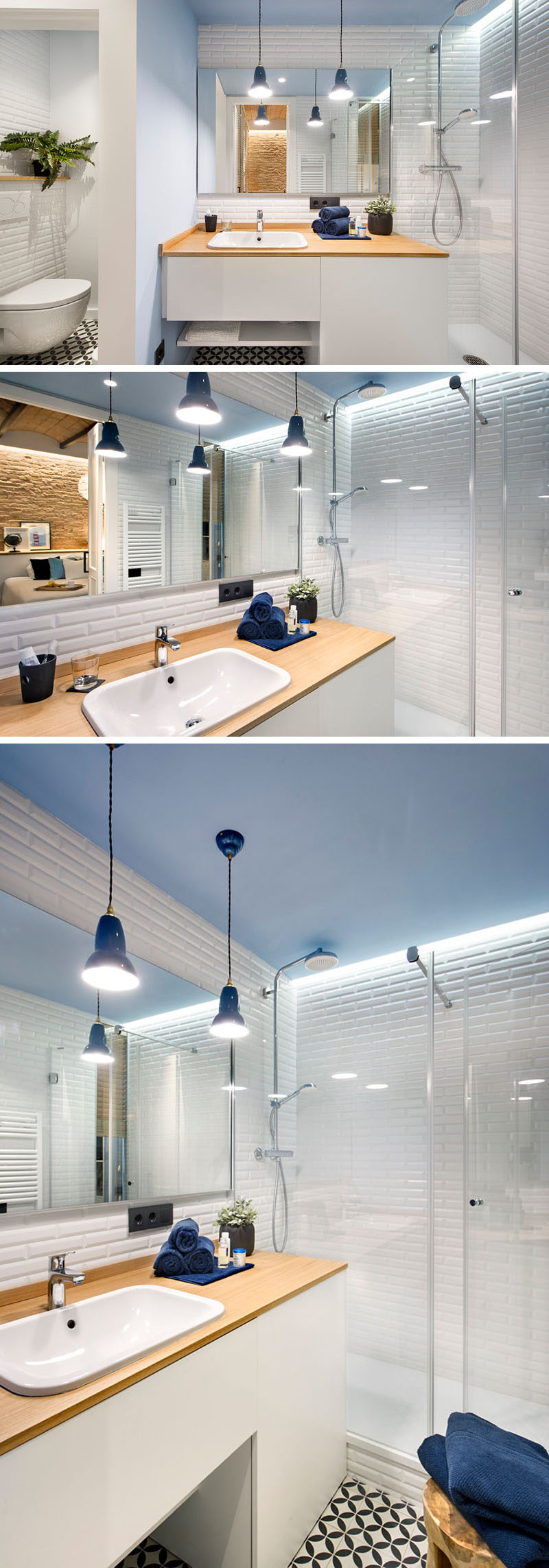 In this small modern bathroom you'll find white tiles and cabinetry, light blue walls and ceiling, and a wood countertop matches the palette of the rest of the apartment. Hanging pendant lights above the sink brighten the space and make it more inviting and plants in the bathroom create a natural vibe and bring a touch of life into the space. The shower is separated from the rest of the bathroom with a glass shower surround.