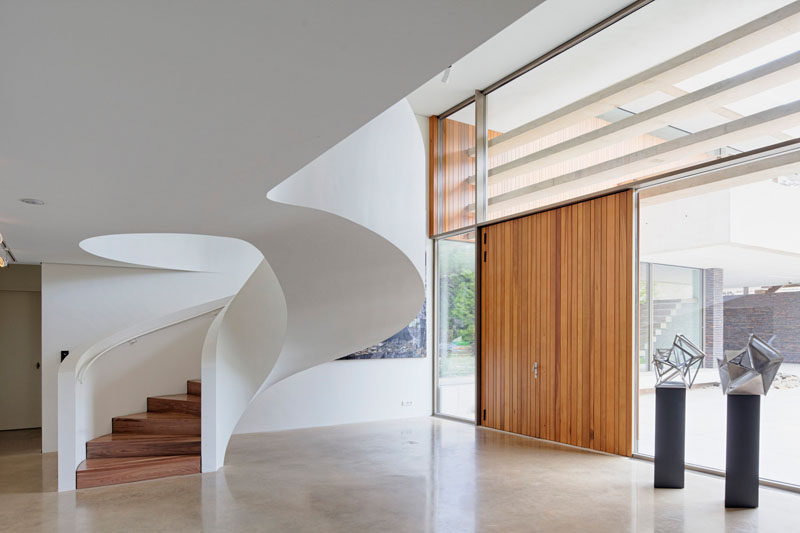 This white modern spiral staircase features a white railing and wood steps to keep the design clean and simple.