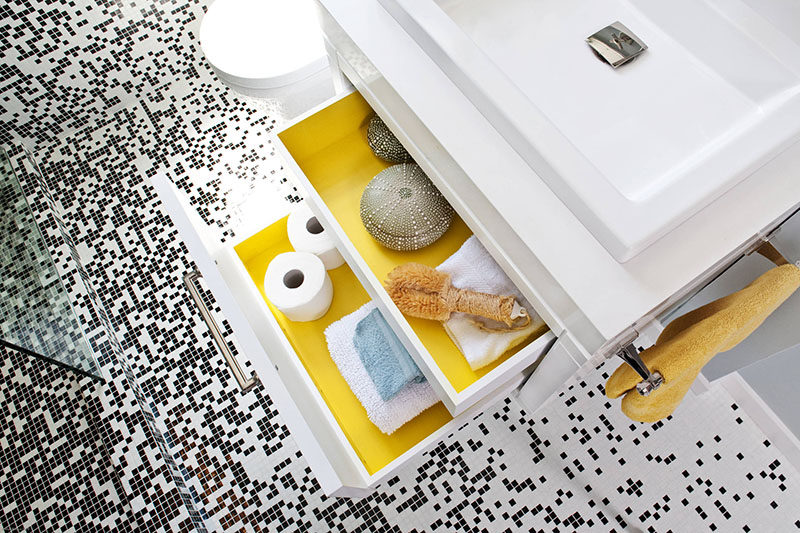 When the drawers in this modern bathroom are closed, the bathroom is primarily black and white with a couple of yellow accents creating an overall look of modern sophistication. But an unexpected pop of color can be seen when opening the drawers that have been painted yellow on the inside.