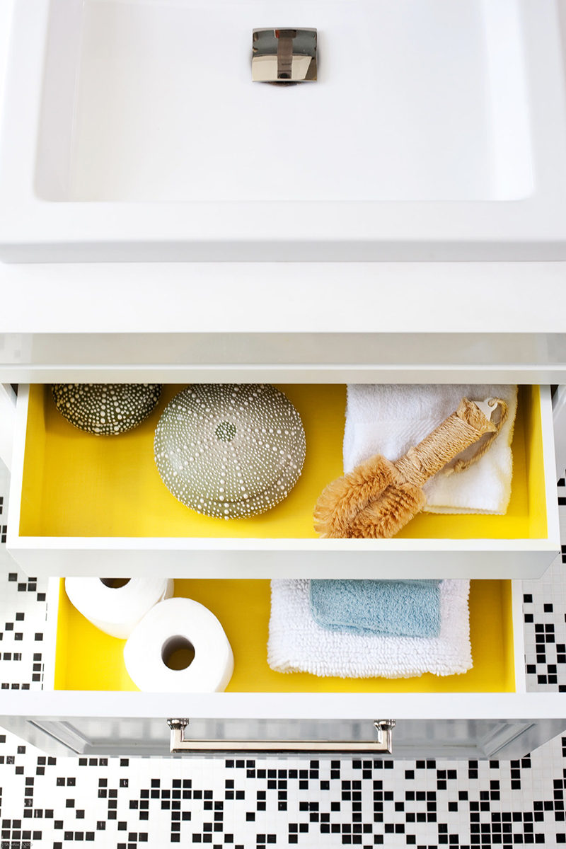 When the drawers in this modern bathroom are closed, the bathroom is primarily black and white with a couple of yellow accents creating an overall look of modern sophistication. But an unexpected pop of color can be seen when opening the drawers that have been painted yellow on the inside.