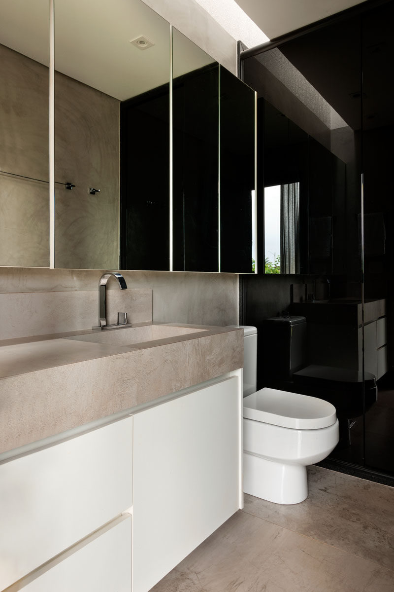 This modern bathroom has a simple colour palette of black, white and natural stone, while a small skylight lets some natural light into the room.