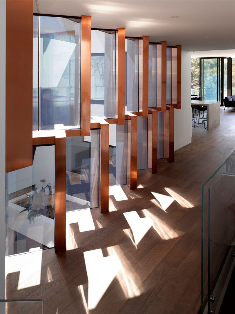 This modern hallway overlooks a landscaped courtyard, while sculptural copper fins filter the light.