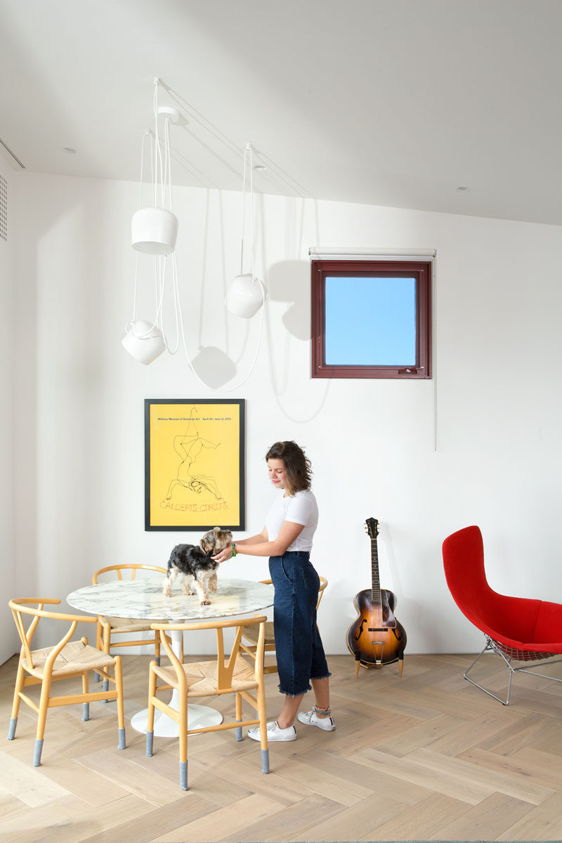 This casual dining room has a round table with wood chairs and white pendant lights that blend in with the walls.