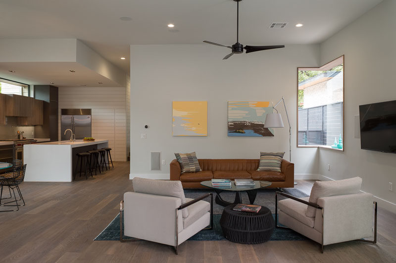 This modern house has an open floor plan, with the living room, dining room and kitchen all sharing the space. A window wrapping around the corner provides natural light to the living room.