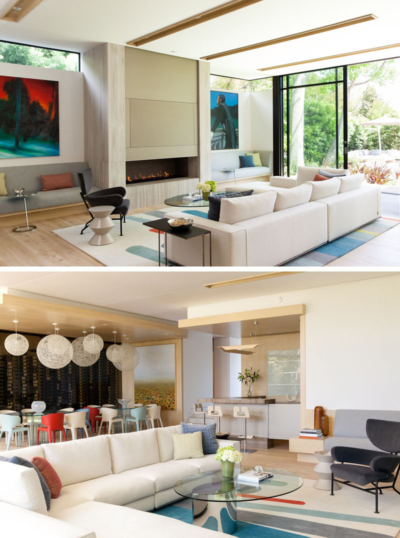 Large sliding glass doors open this modern living room to the backyard, while built-in seating has been included on either side of the fireplace. Behind the couch is the dining area and bar.