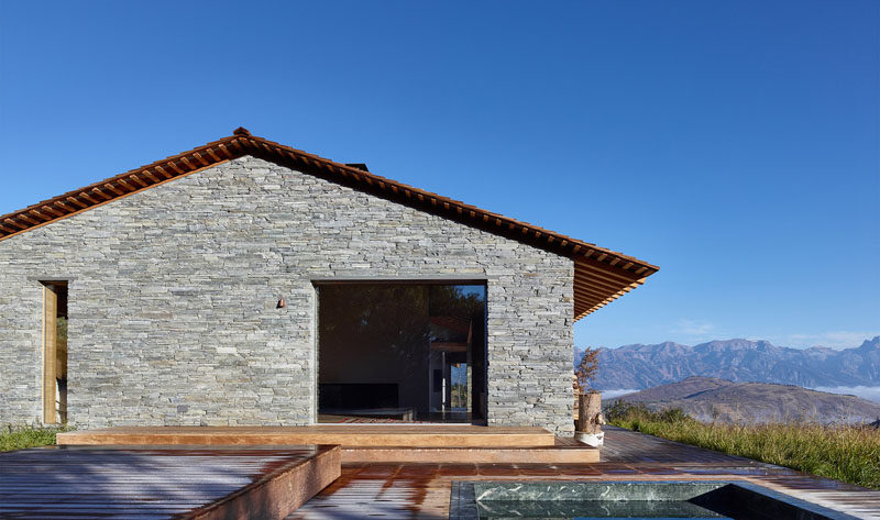 This modern stone and wood house has a deck with a built-in spa.