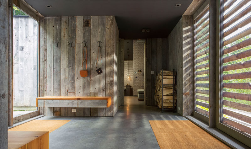 The re-purposed wood siding on the exterior of this modern house continues through to the interior, as seen here in the front entryway, that's central to the home.