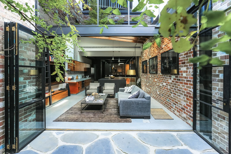 Sam Crawford Architects have transformed what was once a commercial garage sandwiched between terrace houses, into a bright and modern home that's long and narrow, and features a material palette of black steel, recycled brick, concrete and timber.