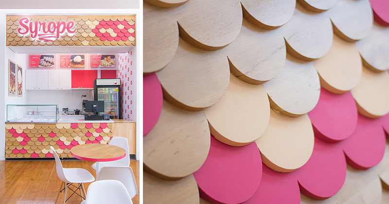 This retail storefront features a bright and colorful design, with a textural scalloped patterned facade made from wood, with some of the pieces painted pink to match the logo, while the remainder of the storefront is white with just a few touches of pink.