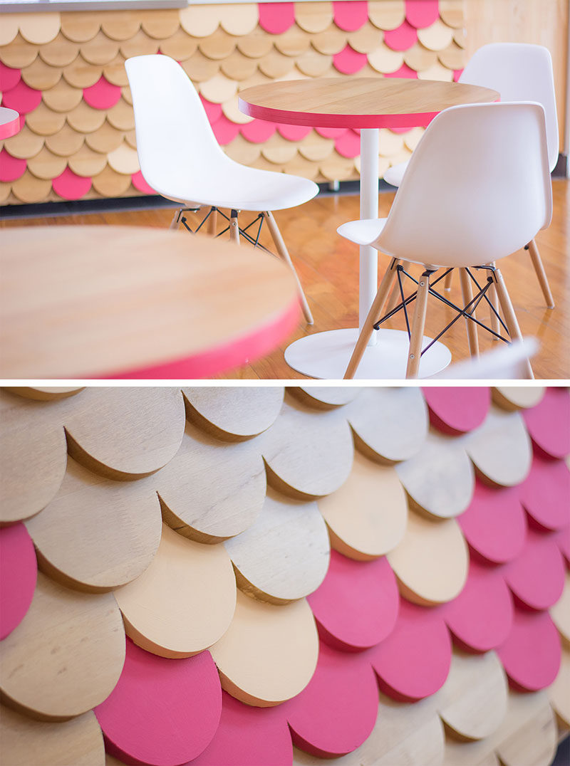 The modern furniture that sits next to this retail store has the same elements of pink, wood and white, that ties into the scalloped facade design.