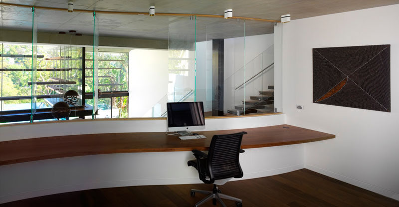 This large home office has a built-in floating wood desk that overlooks the main living room below. 