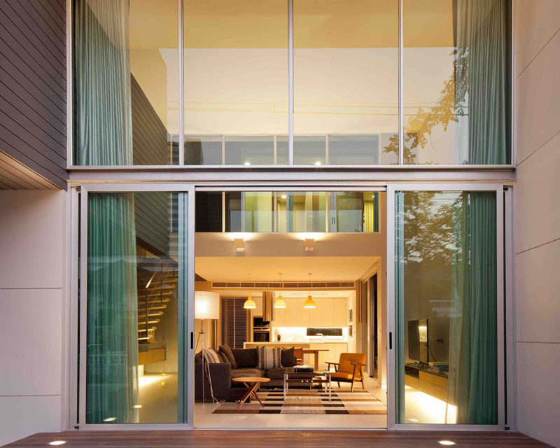 Large windows and sliding glass doors fill the double-height interior of this modern house with plenty of natural light.