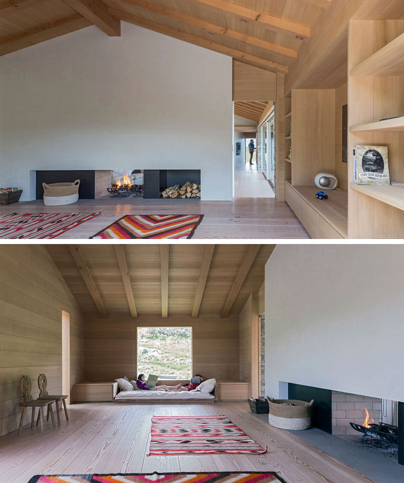 This modern house has a secondary living space, with a double-sided fireplace, built-in book shelves and a built-in day bed under the window.