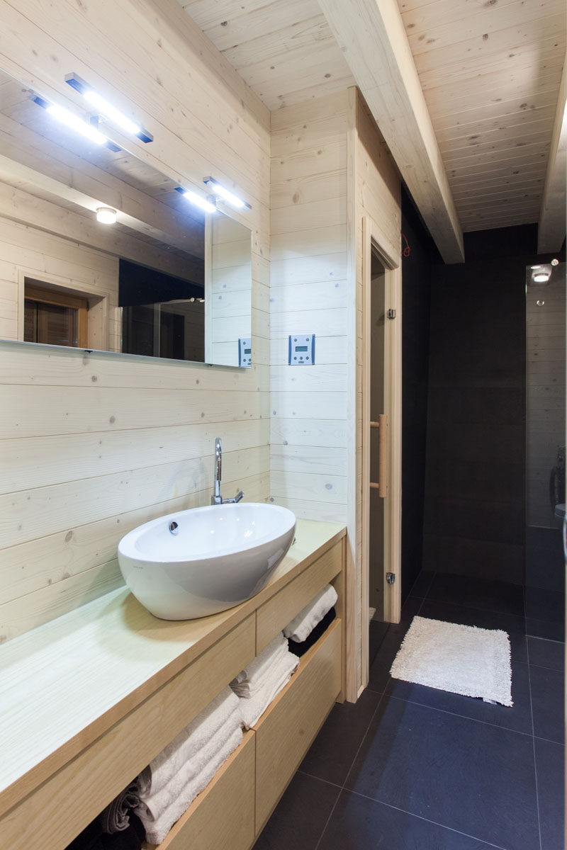 This light wood bathroom has a black shower and flooring for a rustic modern look.