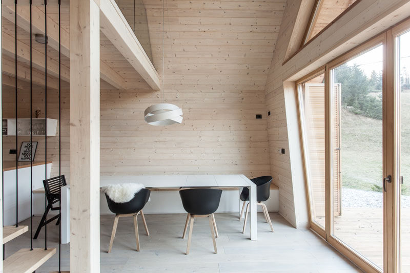 In this modern light wood and white dining room, a bench is built-in along the wall to save room.