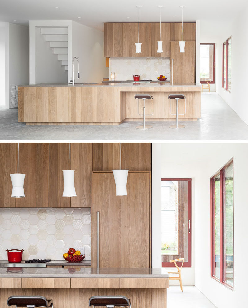 This light wood kitchen has a large island with space for counter stools, a fridge that easily blends into the cabinets, and a light hexagon tiles backsplash.