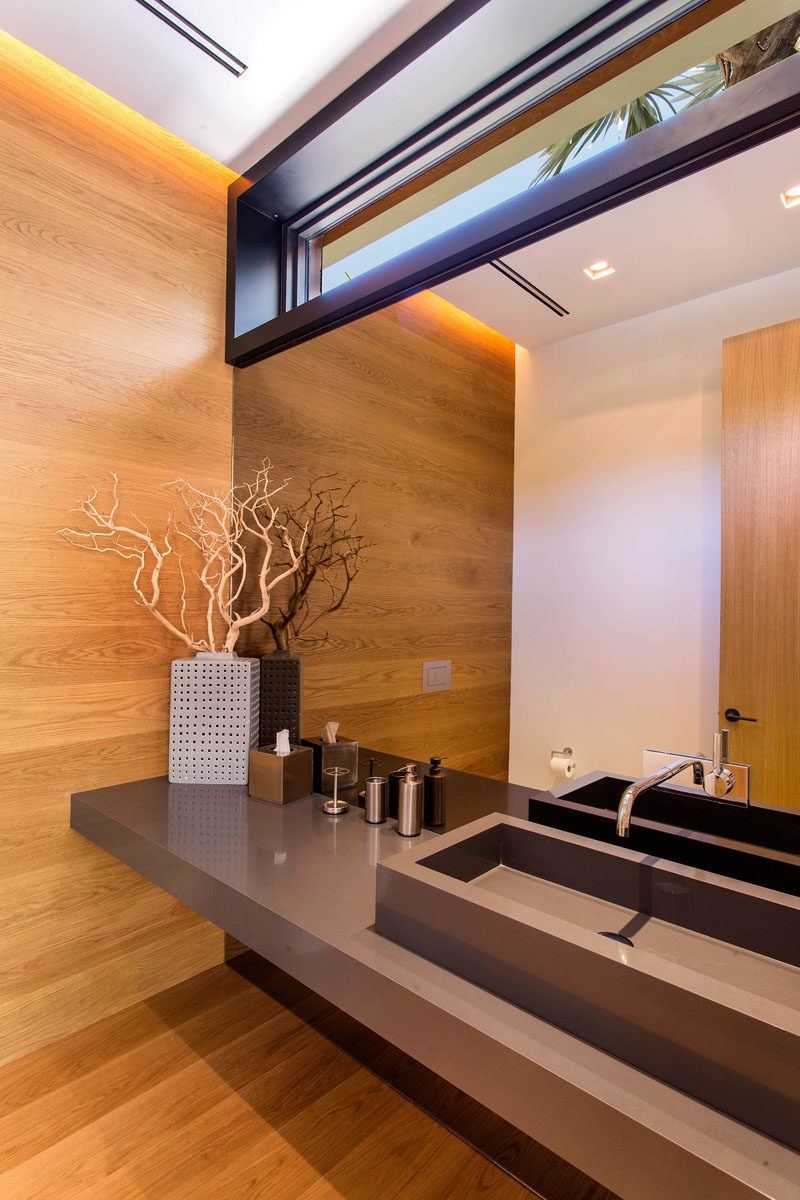 In this modern bathroom, there's hidden lighting in the ceiling that creates a warm glow on the wood wall and floor.