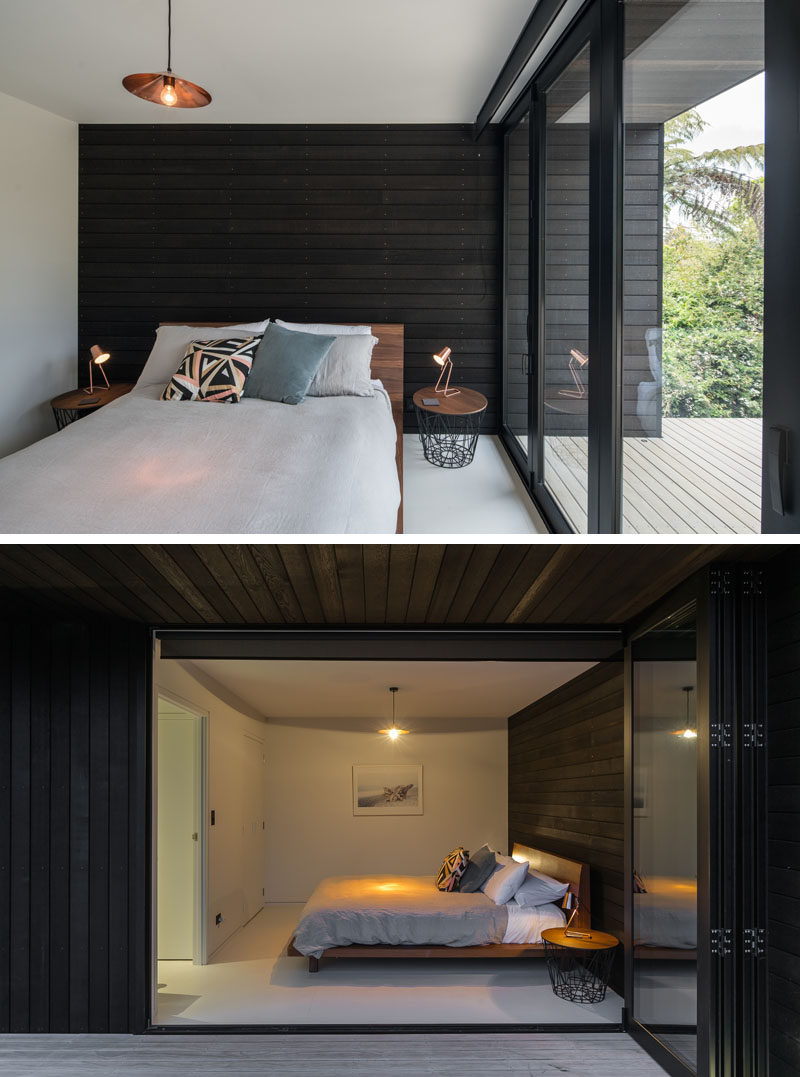 This modern bedroom has an accent wall of black wood that continues through to the exterior of the house.