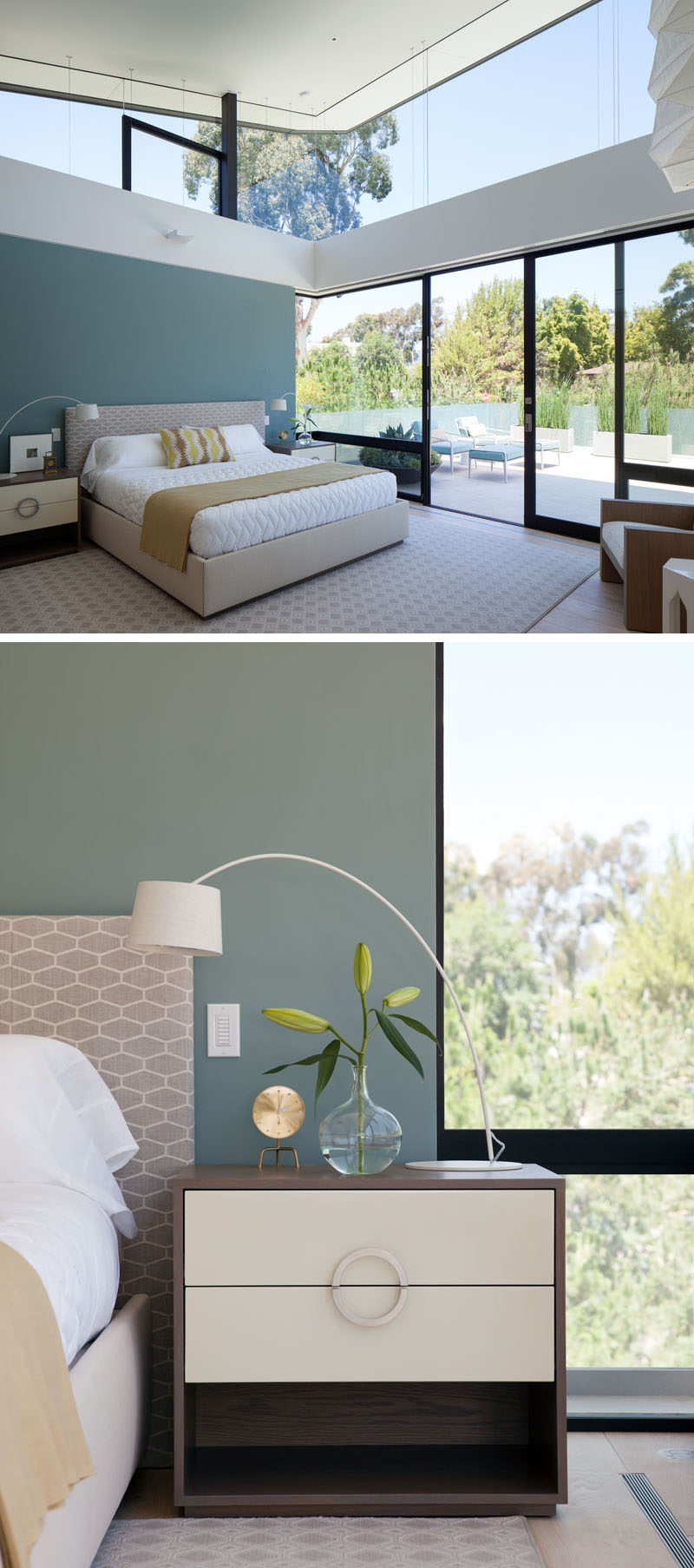 In this modern bedroom, a deep teal blue accent wall has been added for a touch of color, and sliding glass doors open to a private patio with views of the surrounding trees.