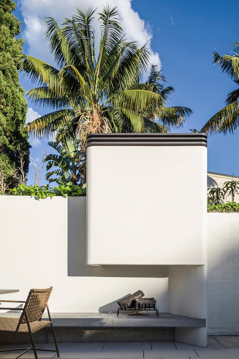 This modern courtyard has a built-in fireplace that sits at the end of a built-in concrete bench.