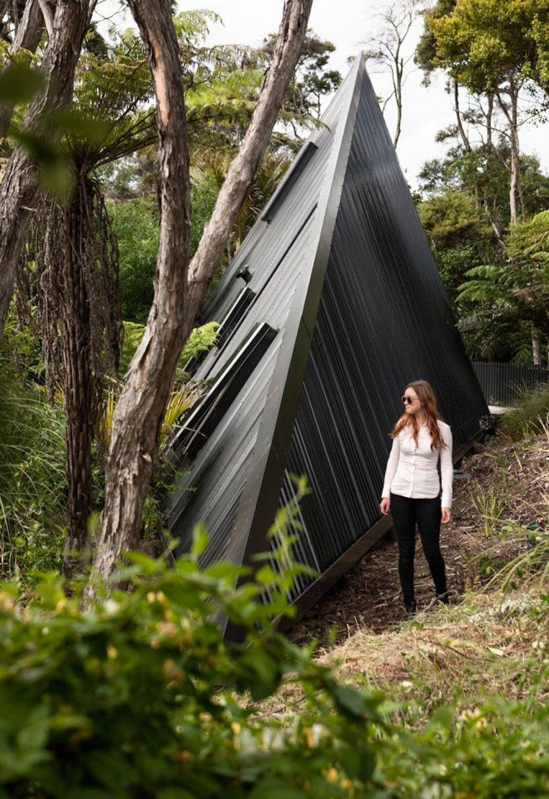 Architect Chris Tate has designed this simple tent-like cabin with a black exterior that's surrounded by trees and located on Waiheke Island, New Zealand.
