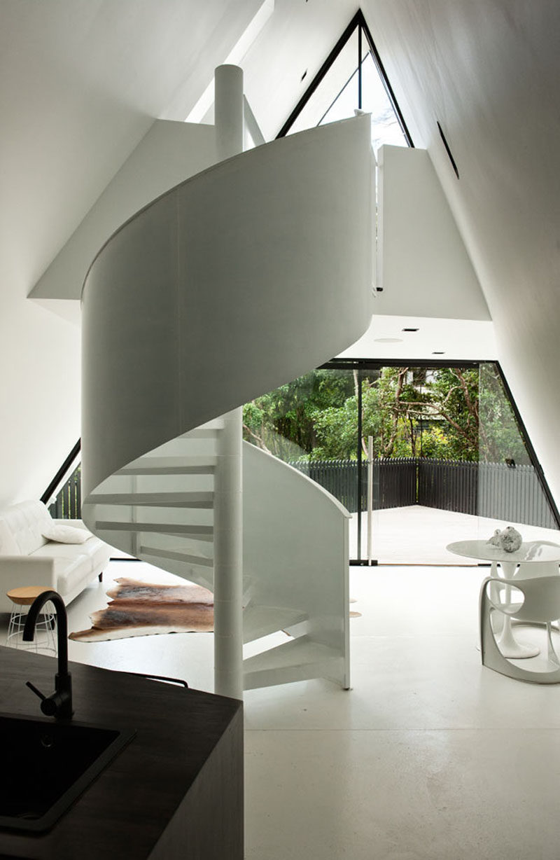 This small and modern cabin has a white spiral staircase that leads to the bedroom.