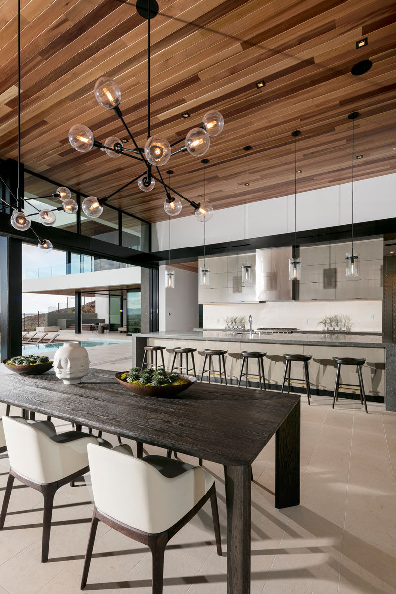 This modern dining room, with a large dark wood table, is anchored in place by two sculptural pendant lights.