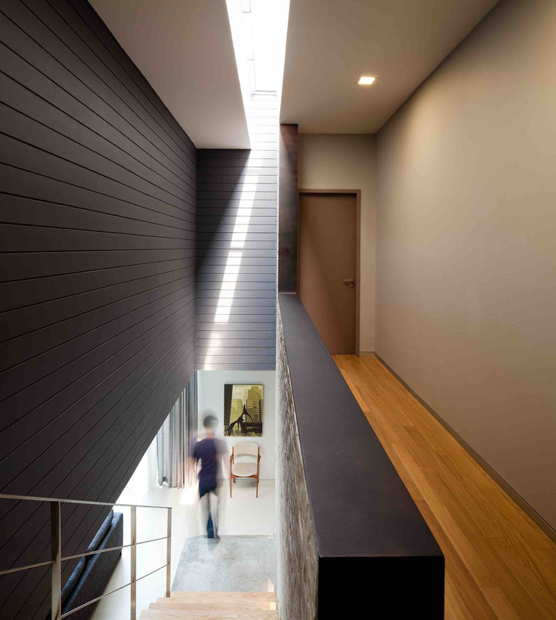 At the top of these concrete and wood stairs, there's an open hallway that leads to the bedrooms, while a skylight adds a touch of natural light to the stairway.